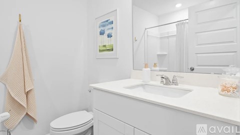 A bathroom with a toilet, sink, and a painting on the wall.