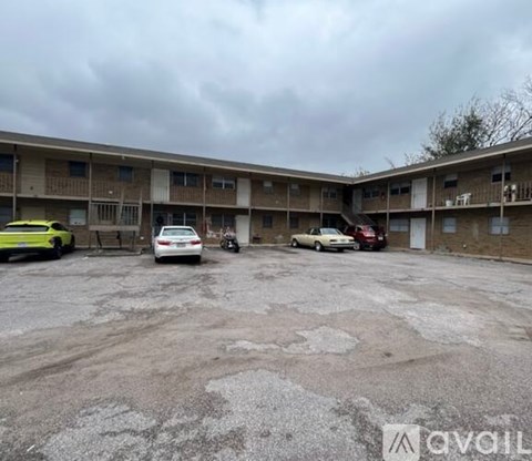 A parking lot in front of apartment buildings with cars parked.