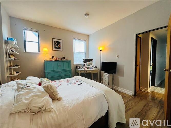 A bedroom with a bed, dresser, and a window.
