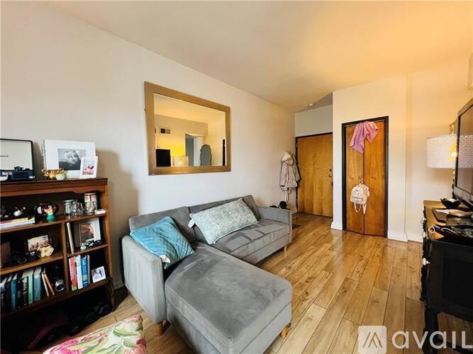 A living room with a grey couch and a wooden floor.
