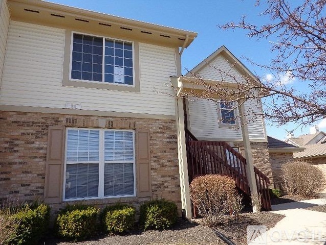 A house with a white siding and a brick wall with a window.
