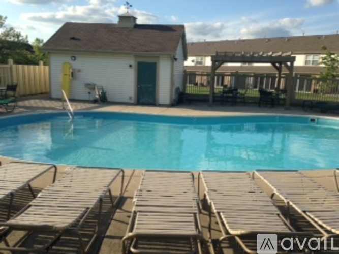 A pool with sun loungers and a white building with a yellow door.