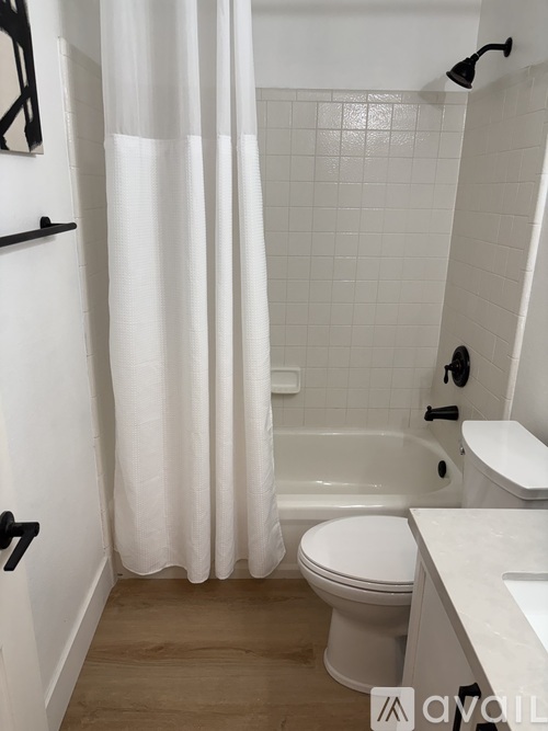 A white bathroom with a toilet, sink, and shower.