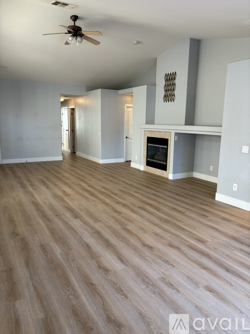 A spacious room with wood flooring and a ceiling fan.