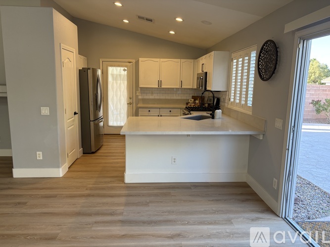 A kitchen with white cabinets and a wooden floor.