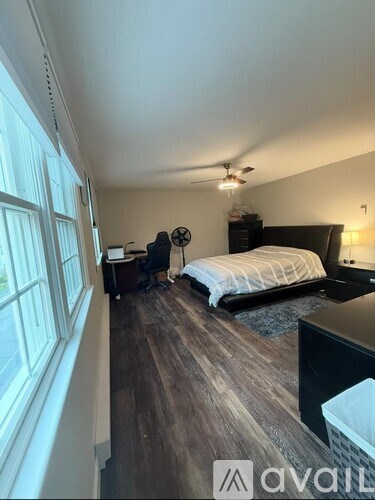 A bedroom with a bed, desk, and window.