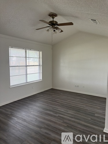 A room with a ceiling fan and a window with blinds.