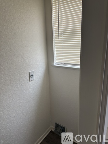 A white wall with a switch and a window with blinds.