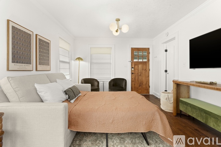 A bedroom with a bed, chair, and a painting on the wall.