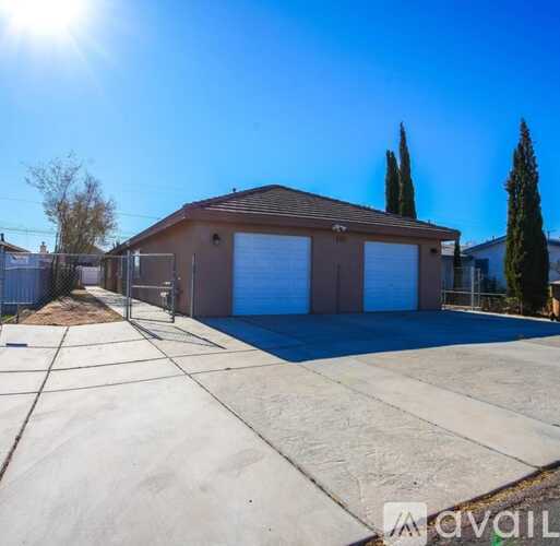 A sunny day at a detached house with a garage and a driveway.