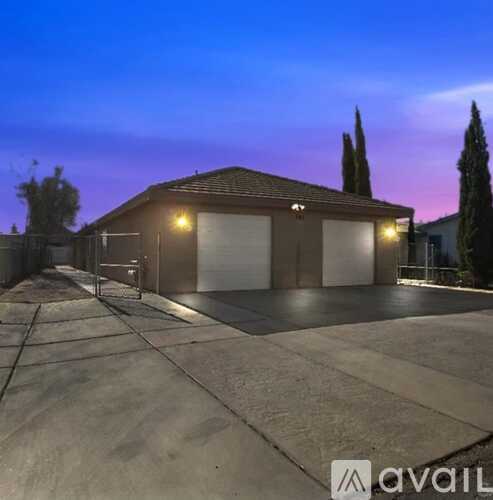 A two-story house with a garage is illuminated by lights at dusk.