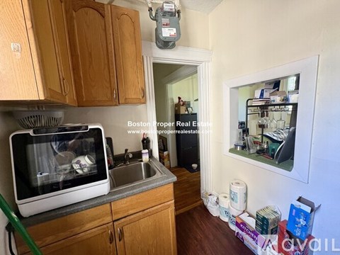 A kitchen with wooden cabinets and a microwave on the counter.
