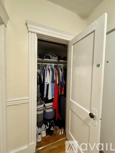 A white closet with clothes and shoes.