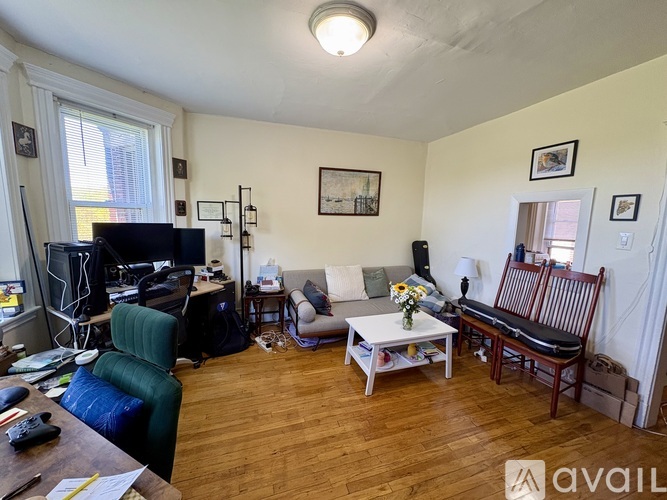 A living room with a green chair, a white couch, a wooden coffee table, and a TV.