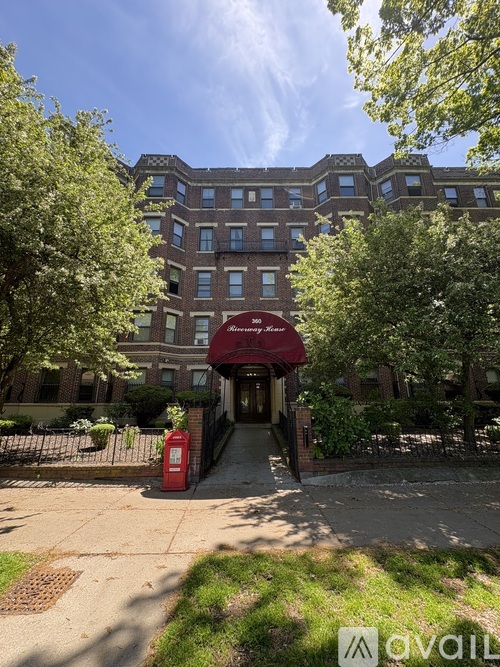 A building with a red awning is surrounded by trees.