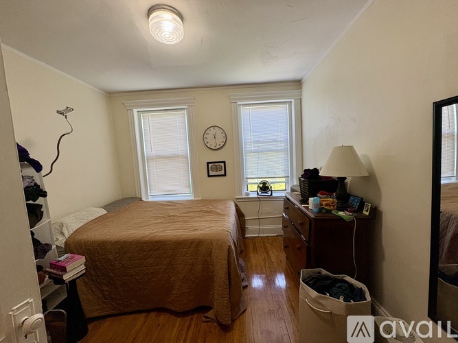 A bedroom with a bed, desk, and window.