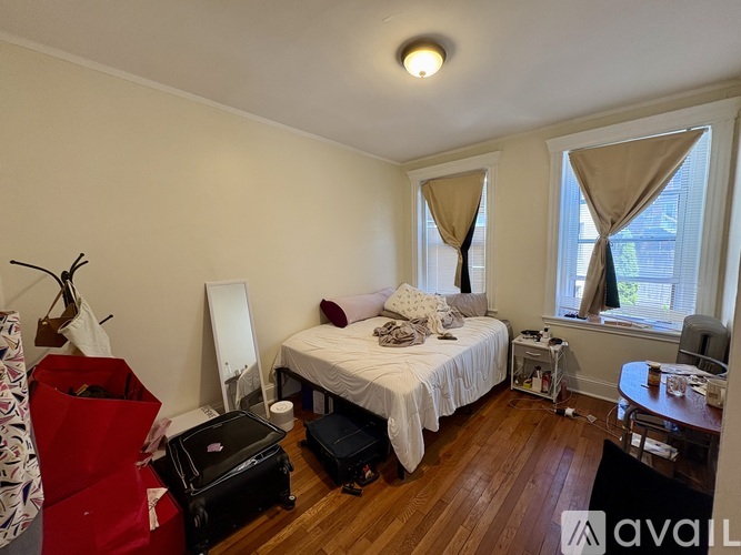 A bedroom with a bed, a chair, and a window with curtains.