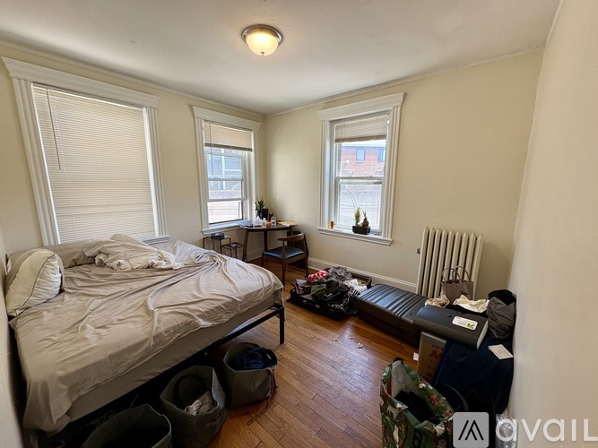 A bedroom with a bed, a window, and a radiator.
