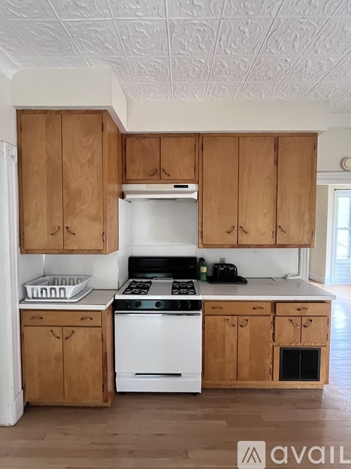 A kitchen with wooden cabinets and a white stove top oven.