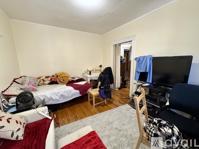 A bedroom with a bed, chair, and television.