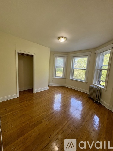 A room with wooden floors and three windows.