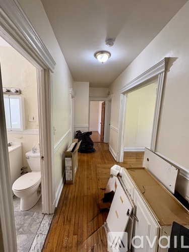 A long hallway with a toilet and a sink.