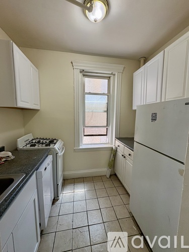 A kitchen with white cabinets and a white fridge.