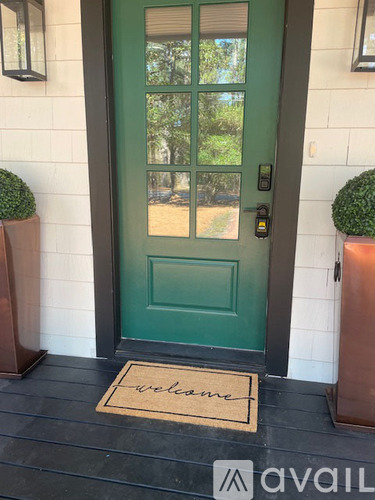 A green door with a welcome mat in front of it.