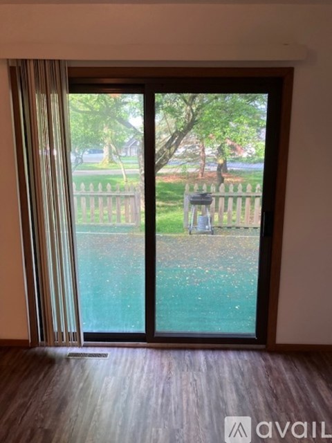A sliding glass door with a view of a green lawn and trees outside.