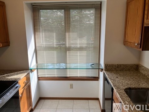 A kitchen with a window covered in blinds.