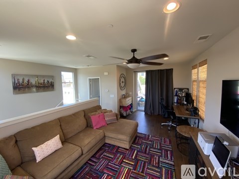 A living room with a brown couch and a colorful rug.