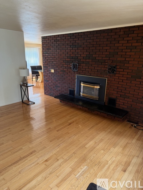 A living room with a fireplace and wooden floors.