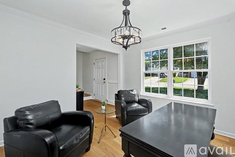 A living room with black leather furniture and a chandelier.