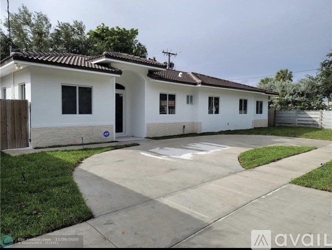 A white house with a brown door and windows is for sale.