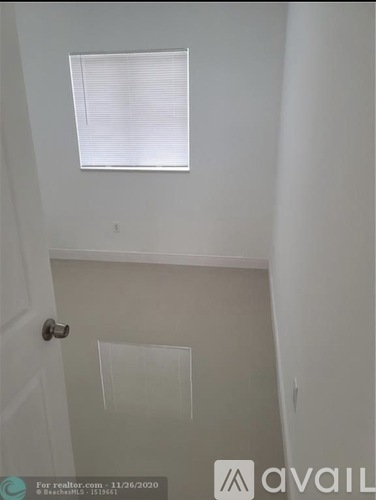 A room with a door and a window with blinds.