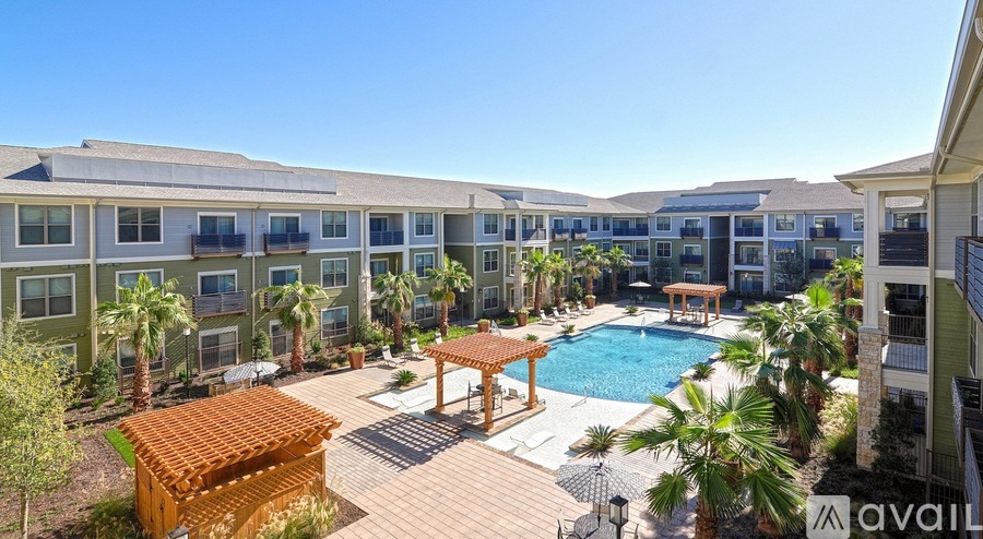 A large outdoor pool surrounded by a wooden deck and palm trees.