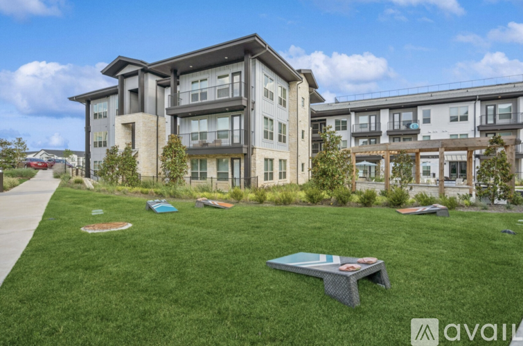 A grassy area in front of apartment buildings with picnic tables.