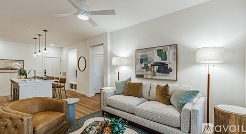 A living room with a brown leather chair, a white couch, and a painting on the wall.