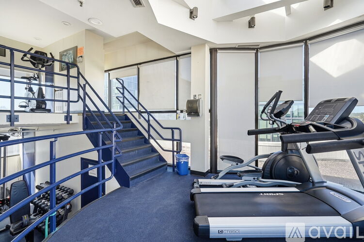 A gym with a treadmill, a staircase, and a railing.