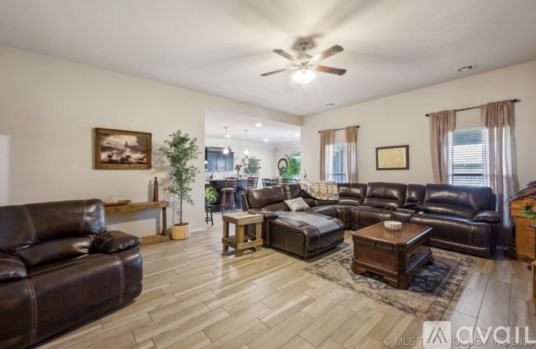 A spacious living room with a variety of seating options and a ceiling fan.