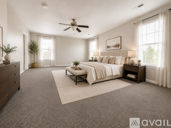 A spacious bedroom with a large bed, a ceiling fan, and a window with curtains.