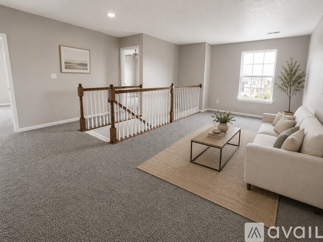 A living room with a carpeted floor, a white couch, a coffee table, and a wooden staircase.