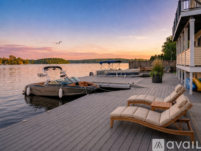 A wooden deck with two sun loungers and a boat docked at a pier.