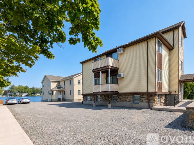 A building with a balcony is surrounded by a gravel lot.