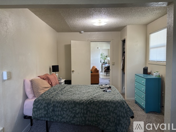 A bedroom with a bed, chair, and nightstand.