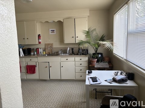 A kitchen with white cabinets and a white table with a plant on it.