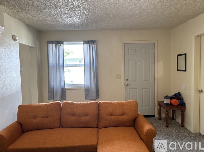 A living room with a couch, a table, and a window with curtains.