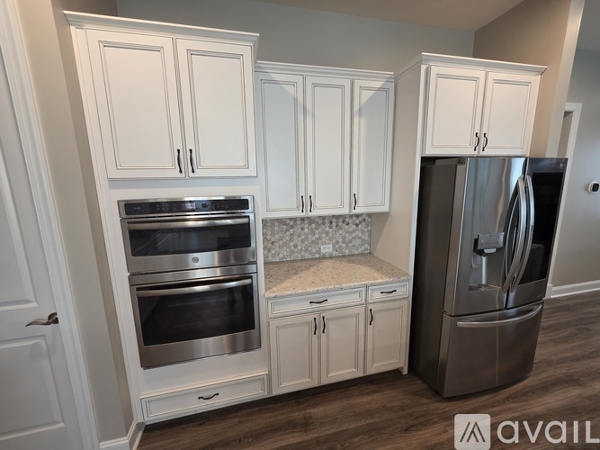 A kitchen with white cabinets and a stainless steel refrigerator.