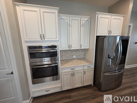 A kitchen with white cabinets and a stainless steel refrigerator.