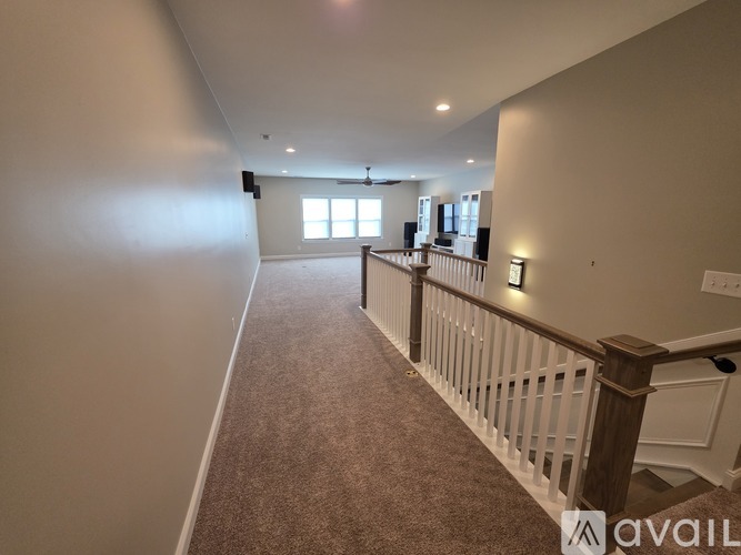 A spacious room with a carpeted floor and a staircase with a railing.